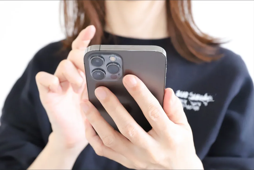 連絡しようか迷いながらスマートフォンを持つ手元